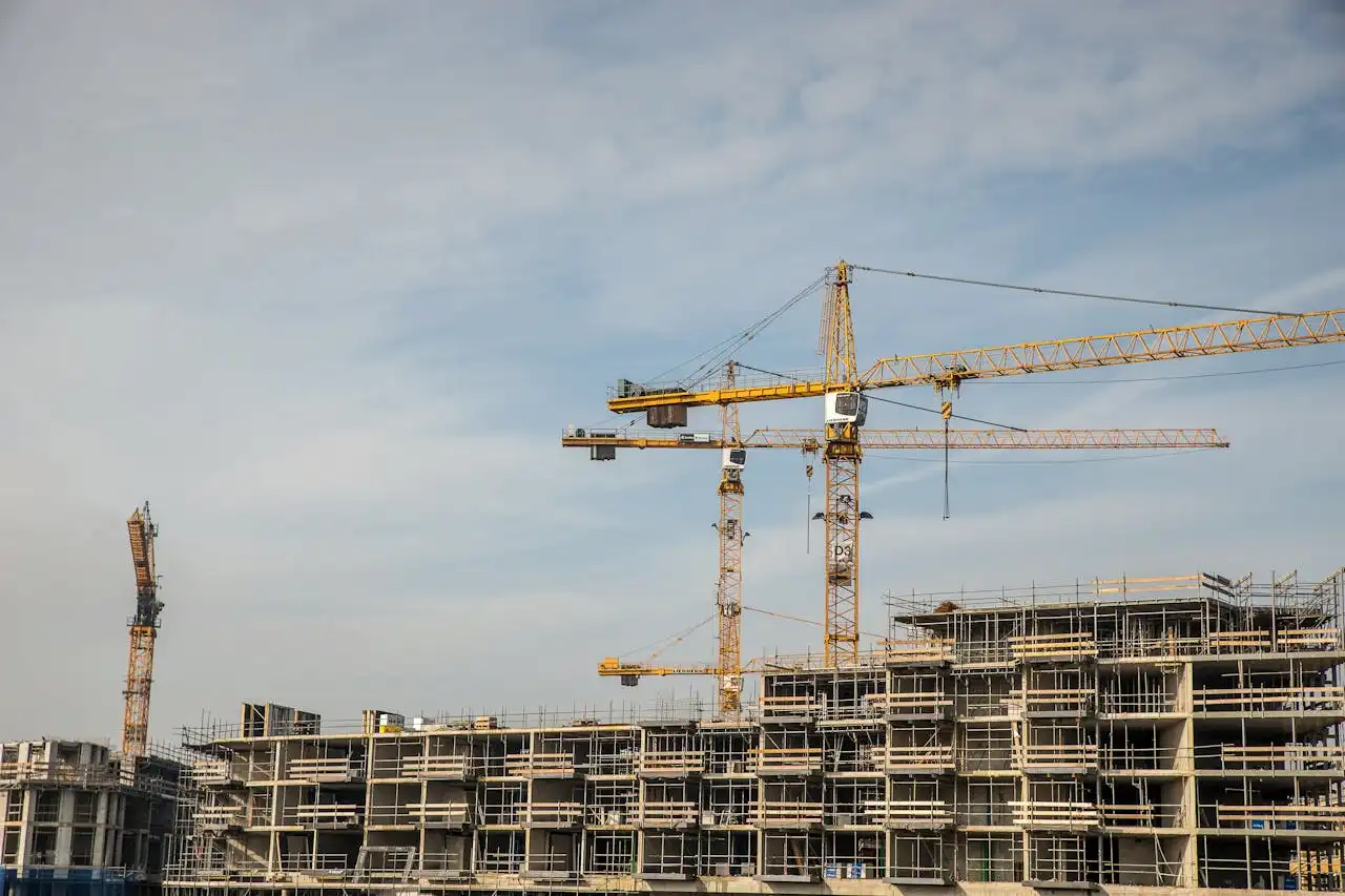 Complejo de edificios en construcción con varias grúas torre.