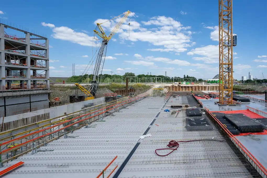 Obra civil en proceso con grúas y estructura de hormigón armado.